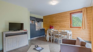 Un espacio habitable compacto con kitchenette, comedor y zona de estar.