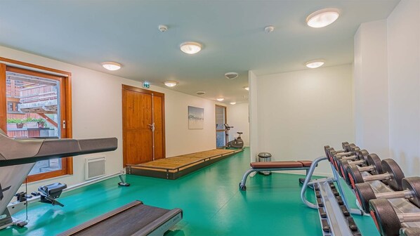 Un gimnasio con equipo de ejercicio, una caminadora, una bicicleta estática y una máquina de remo.