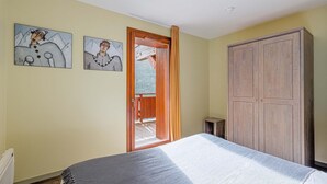 Un dormitorio con cama, armario y dos cuadros en la pared.