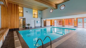 Una piscina interior con paneles de madera, suelo de baldosas y un banco a la izquierda.