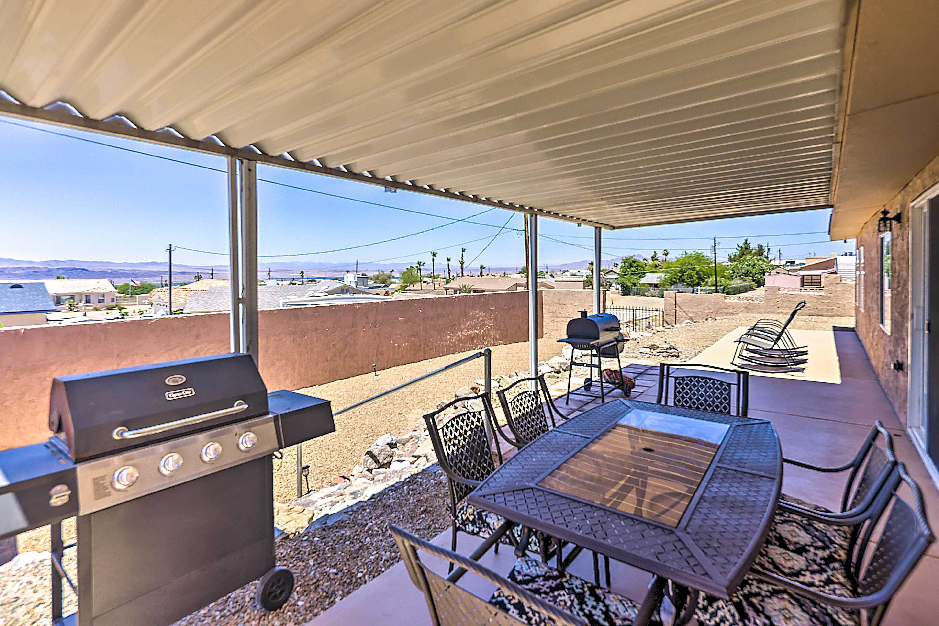 An outdoor patio with a grill, table, and chairs.