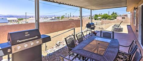 An outdoor patio with a grill, table, and chairs.