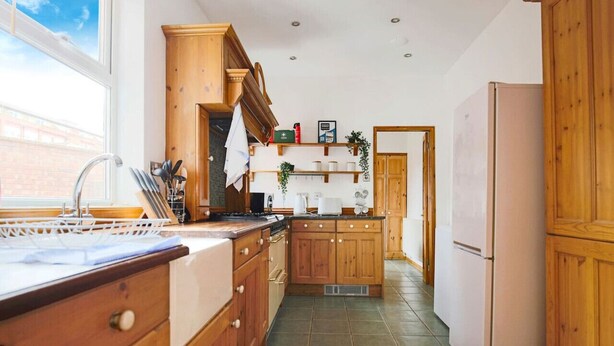 A kitchen with wooden cabinets, a sink, and a refrigerator.