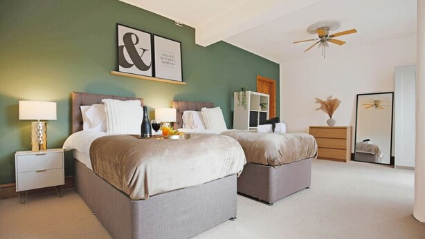 Ein Schlafzimmer mit zwei Betten, einem Deckenventilator und einem Wandbild.
