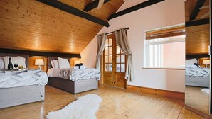 Ein Schlafzimmer mit zwei Betten, Holzbalken, einem großen Fenster und einem Spiegel.