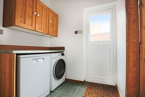 A laundry room with a washing machine, wooden cabinets, and a door leading outside. - Central House • Sleeps 9 • FreeParking • Pool Table • Fast Wifi • Balcony • VirginTV • Yoko Property (Northampton)