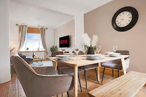 A dining area with a wooden table, chairs, and a wall-mounted clock. - Central House • Sleeps 9 • FreeParking • Pool Table • Fast Wifi • Balcony • VirginTV • Yoko Property (Northampton)