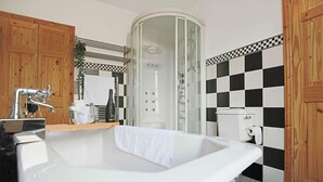 Ein Badezimmer mit freistehender Badewanne, einer Duschkabine und einer Rückwand mit Schachbrettfliesen.
