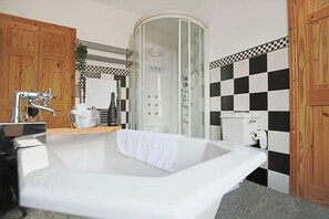 A bathroom with a freestanding bathtub, a glass-enclosed shower, and a checkered tile backsplash.