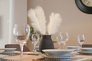 A dining table set with plates, glasses, and a vase with white feathers. - Central House • Sleeps 9 • FreeParking • Pool Table • Fast Wifi • Balcony • VirginTV • Yoko Property (Northampton)