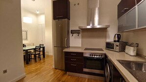 A compact kitchen with a refrigerator, oven, microwave, and a sink.