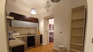 A compact kitchen with wooden flooring, a built-in dishwasher, and a microwave.
