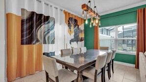 Una sala da pranzo con tavolo in vetro, sei sedie, un'opera d'arte astratta alle pareti e una vista attraverso ampie finestre.