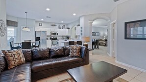 A modern apartment with a leather sofa, a dining area, a kitchen, and a living room. - Luxury Private Villa With Pool on Windsor Hills Resort, Orlando Villa 5785 (Kissimmee)