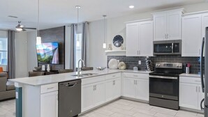 A modern kitchen with white cabinets, a black stove, a microwave, and a dishwasher. - Rent This Luxury 5 Star House on Champions Gate Resort, Orlando House 5786 (Davenport)