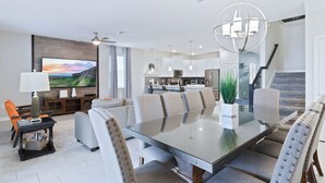 A modern kitchen with stainless steel appliances, a dining area with a glass table, and a living room with a flat-screen TV. - Rent This Luxury 5 Star House on Champions Gate Resort, Orlando House 5786 (Davenport)
