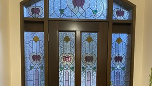 A brown wooden door with stained glass panels and a small bench in front.