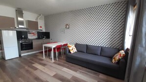 Un espace de vie compact comprenant un coin cuisine, un coin repas et un canapé.