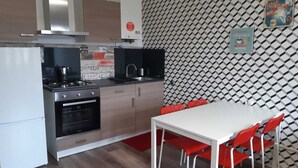 Une cuisine moderne avec un coin repas, comprenant un mur à motifs, une table blanche et des chaises rouges.