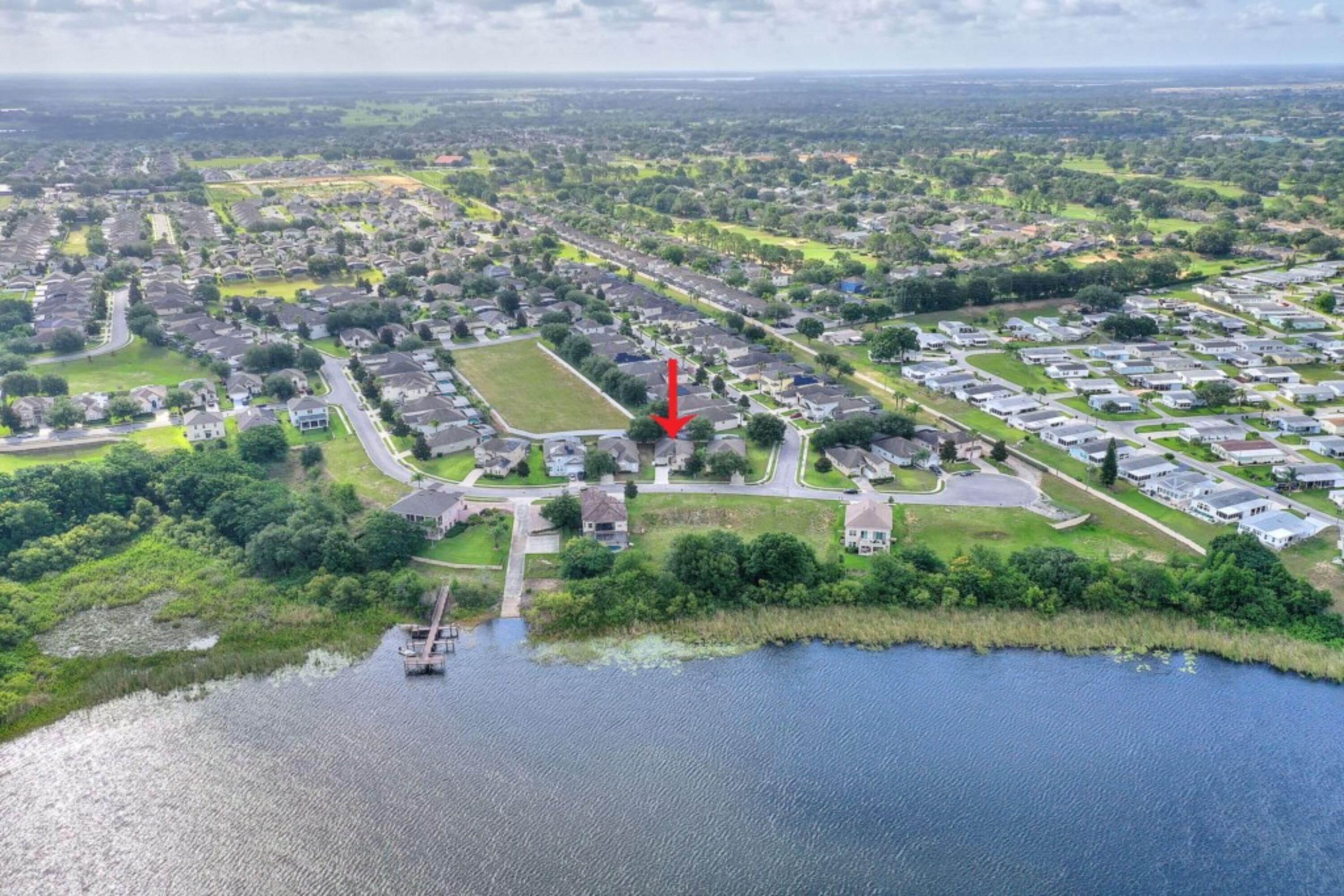 Vue aérienne d’un quartier résidentiel avec des maisons, des routes et une étendue d’eau.