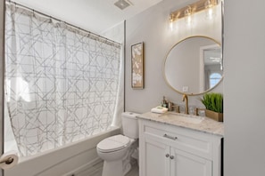 A bathroom with a shower curtain, toilet, sink, and mirror. - Gold Rest at Calabay Parc Tower Lake by Shine Villas 412 (Haines City)