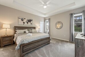 A bedroom with a large bed, a world map on the wall, a ceiling fan, and a view of the outdoors through a window. - Gold Rest at Calabay Parc Tower Lake by Shine Villas 412 (Haines City)