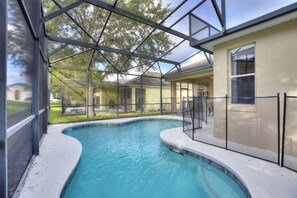 A swimming pool with a glass enclosure, surrounded by a house with a beige exterior and a window. - Gold Rest at Calabay Parc Tower Lake by Shine Villas 412 (Haines City)