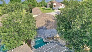 A residential property with a swimming pool, surrounded by lush greenery and a view of a large lake.