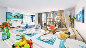 A modern living room with a dining area, large windows, and a city view. - Waikiki condo w/ balcony, pool, & beach steps away (Honolulu)