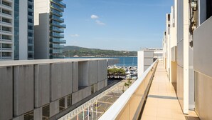 Un bâtiment moderne doté d’un balcon donnant sur une marina et offrant une vue dégagée sur la mer.