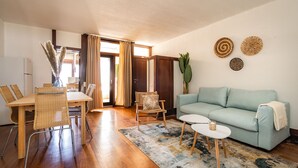 Un salon avec un canapé bleu clair, une table à manger avec des chaises, une table basse et une grande plante.