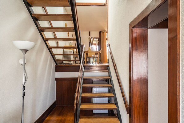 A wooden staircase with a handrail, a white floor lamp, and a radiator on the landing.