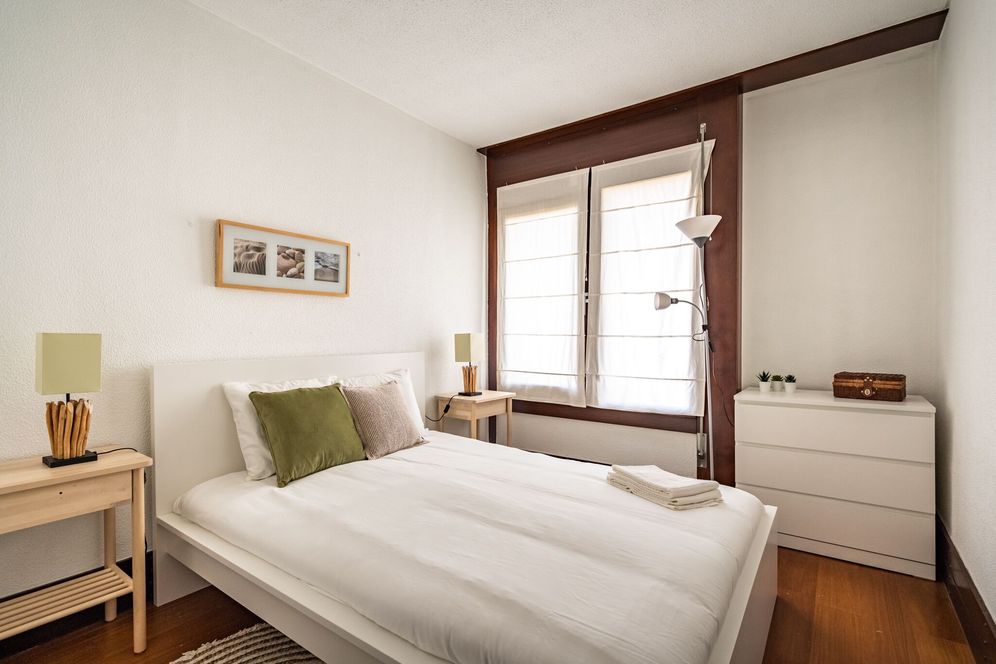 Une chambre à coucher bien rangée, avec un lit, une table de chevet, une lampe et une commode.
