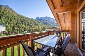 A wooden deck with a table and chairs, overlooking a forested mountain. - Apartment "Edelweiß" with Slope Access, Private Terrace & Wi-Fi (Pfelders)