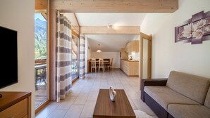 Una sala de estar moderna con un sofá, una mesa de centro de madera, un televisor y un comedor con sillas y una mesa.
