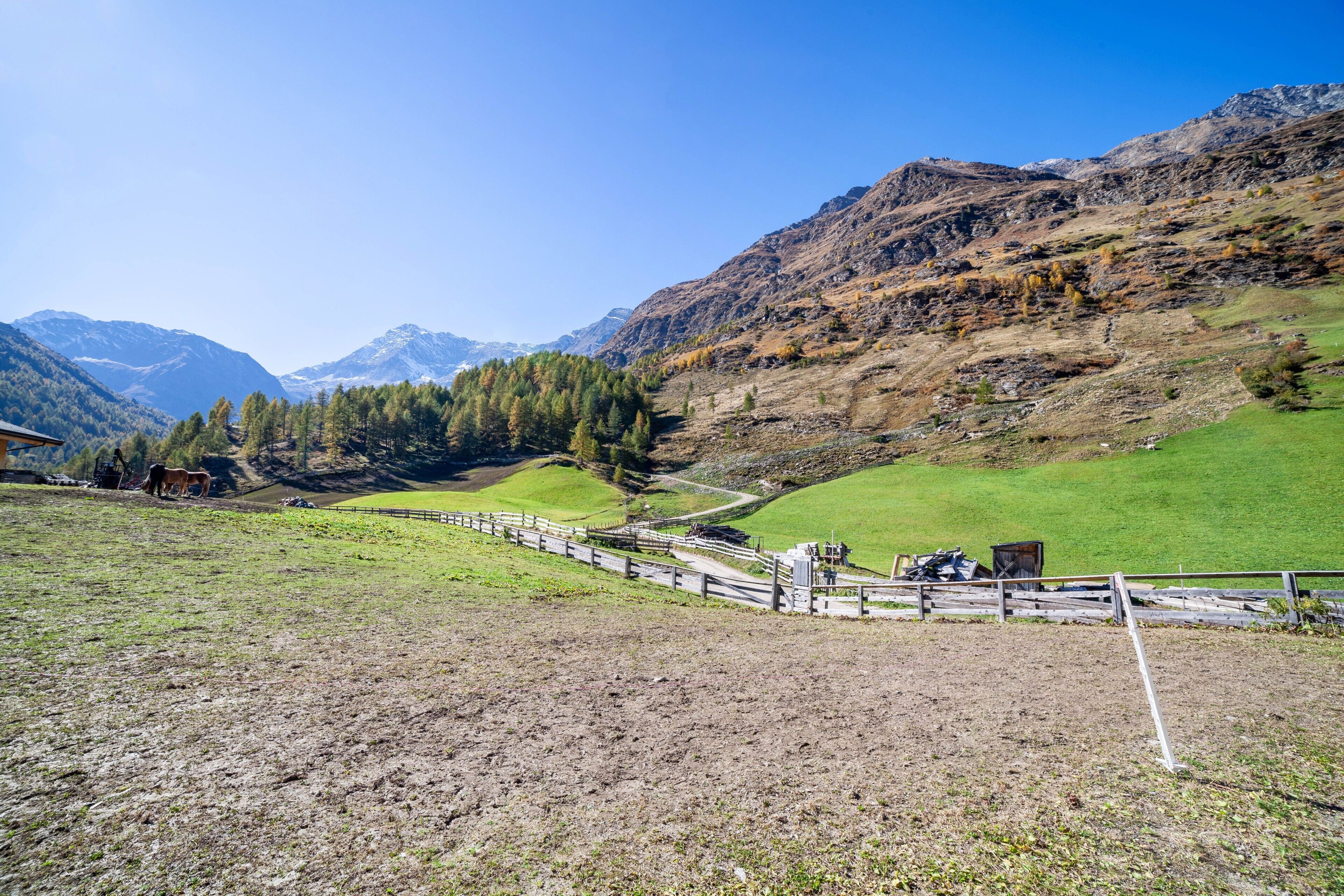 A mountainous landscape with a fenced area, a building, and a clear sky.