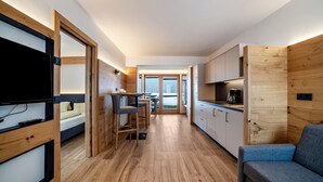 A modern kitchen with wooden cabinetry, a dining area with a table and chairs, and a sofa.