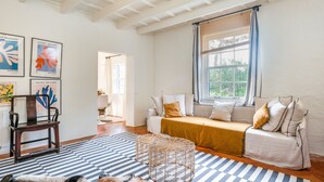 A room with a sofa, a wooden chair, a patterned rug, and artwork on the wall. - Villa Torret with workspace, pool, terrace, and Wi-Fi (Sant Lluis)