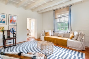 A room with a sofa, a wooden chair, a patterned rug, and artwork on the wall. - Villa 'Torret' with Workspace, Pool, Terrace, and Wi-Fi (Sant Lluis)