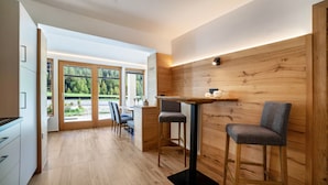 A modern kitchen with wooden accents, a bar area with stools, and large sliding glass doors leading to a garden. - Apartment 'Lazins' with Private Terrace & Wi-Fi (Pfelders)