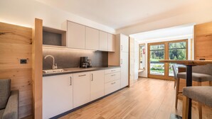 A modern kitchen with wooden cabinets, a built-in stove, and a dining area with a table and chairs. - Apartment 'Lazins' with Private Terrace & Wi-Fi (Pfelders)