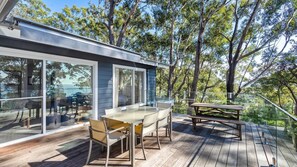 Enjoy outdoor dining and social gatherings on this elevated deck with a clear view of the surrounding trees and sky.
