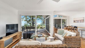 Relax in this stylish living room with a large flat-screen TV, wicker sofa, and dining area.