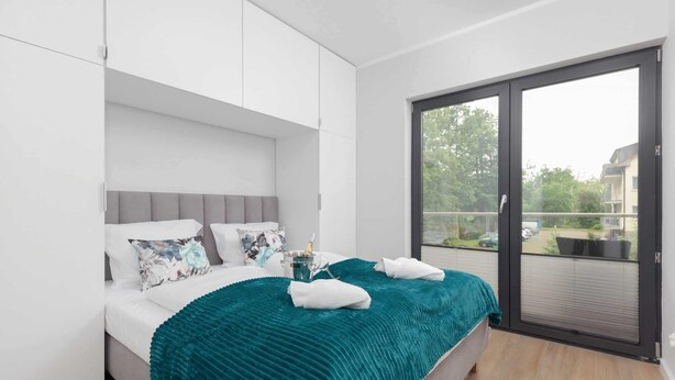 Une chambre moderne avec un lit, une grande fenêtre et un balcon.