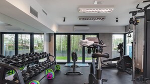 Une salle de sport équipée de matériel d’exercice, dotée de grandes fenêtres et d’un système de climatisation.