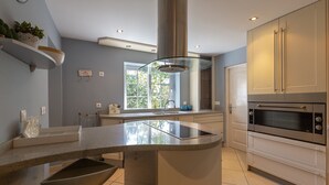 A modern kitchen with a central island, built-in oven, and a window providing natural light. - Villa 'Del Sol - Entre Tu y Yo' with Sea View, Heated Pool, 3 Terraces & Wi-Fi (Benalmádena)