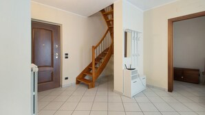 Una habitación con una escalera de madera, un armario blanco y una puerta.