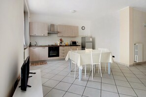 Une cuisine moderne avec des meubles de couleur bois clair, une table à manger avec des chaises et un four encastré.