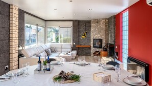 A dining area with a stone fireplace, a sofa, and a table set for a meal. - Villa 'Luxury Rock Tirri' with Private Pool, Covered Terrace, and Wi-Fi (Reus)