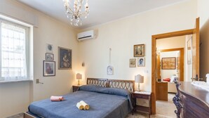 A bedroom with a bed, bedside tables, a chandelier, and framed pictures on the wall. - GuestHost - Bella Vista Apartment with balcony SEA VIEW (Otranto)